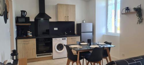 a kitchen with a table and a stove and a washer at La Campagne à la ville dans pavillon avec jardin Clos et privatif in Héricourt