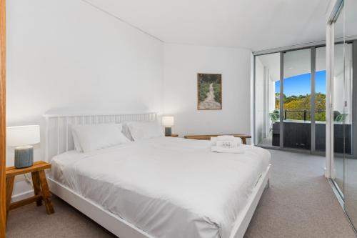 um quarto com uma cama branca e uma grande janela em Cotton Beach 53 by Kingscliff Accommodation em Casuarina