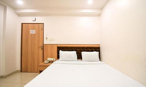 a bedroom with a large white bed and a wooden door at FabHotel Stay Inn International in Kolkata