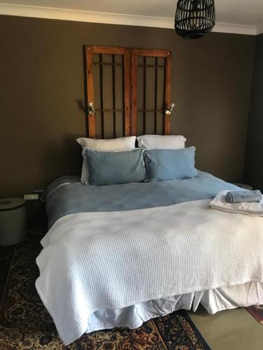 um quarto com uma cama com lençóis brancos e almofadas azuis em Pecan Tree Parys em Parys