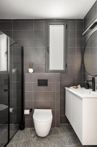 a bathroom with a toilet and a sink and a window at Mate GEORGE - By HOMY in Tel Aviv