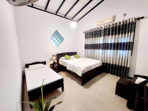a bedroom with two beds and a window at Sky White Villa in Galle