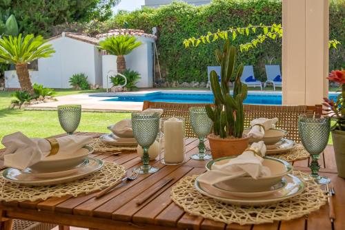 una mesa de madera con platos y servilletas. en VACATION MARBELLA I Villa Faldo, Golf Valley, Private Pool, 24H Security, 10 min from the Marina, en Marbella