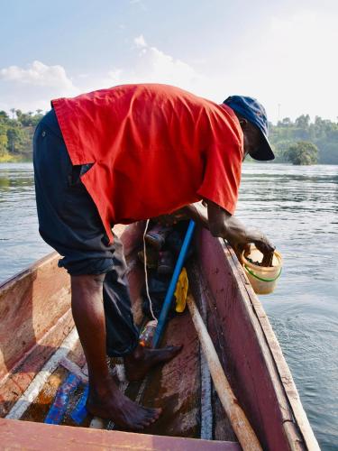 Un homme est debout dans un bateau dans l'eau dans l'établissement Home On The Nile Ernest Hemingway Suite, à Jinja