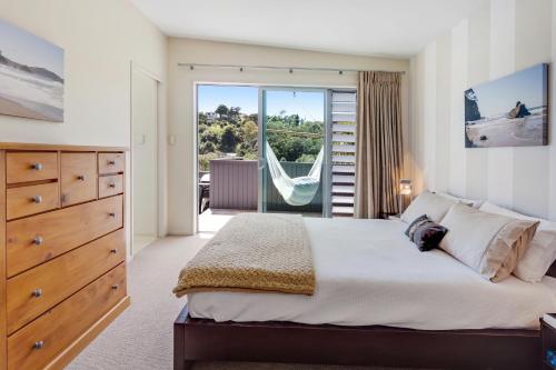 a bedroom with a large bed and a sliding glass door at Lavish Luxury - Parekura Bay Holiday Home in Rawhiti