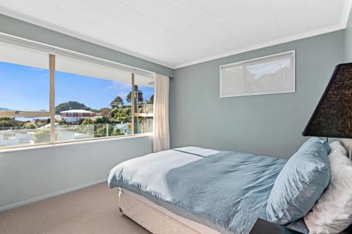 ein Schlafzimmer mit einem Bett und einem großen Fenster in der Unterkunft Seaside Sounds - Picton Upstairs Unit in Picton