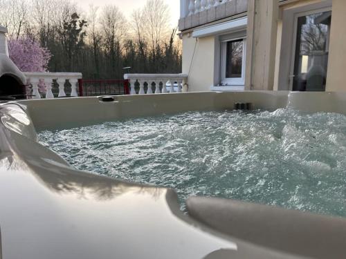 a tub filled with water in front of a house at Les berges du canal, maison avec Jacuzzi in Couvrot