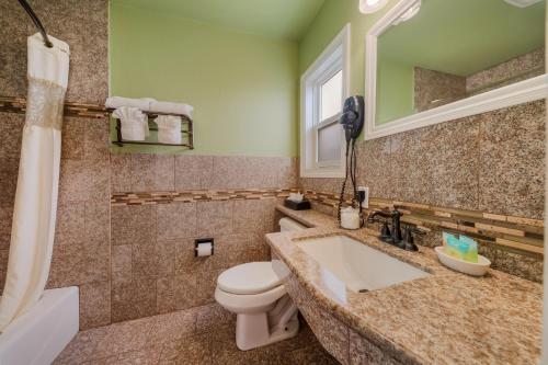 Carmel Inn & Suites في كرمل: حمام مع حوض ومرحاض ومرآة