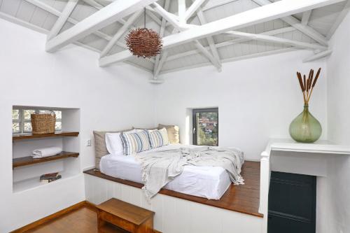 a white bedroom with a bed and a fireplace at Villa John's Skopelos Stafilos in Skopelos Town