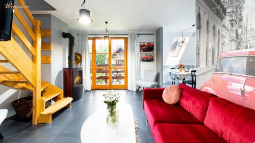 a living room with a red couch and a table at Wonder Home - Domki górskie z kominkami na kameralnym osiedlu - plac zabaw na terenie kompleksu in Karpacz