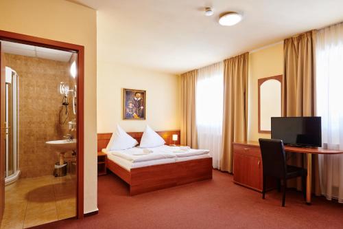 a hotel room with a bed and a desk and a television at Hotel Zlatá Hvězda in Vimperk