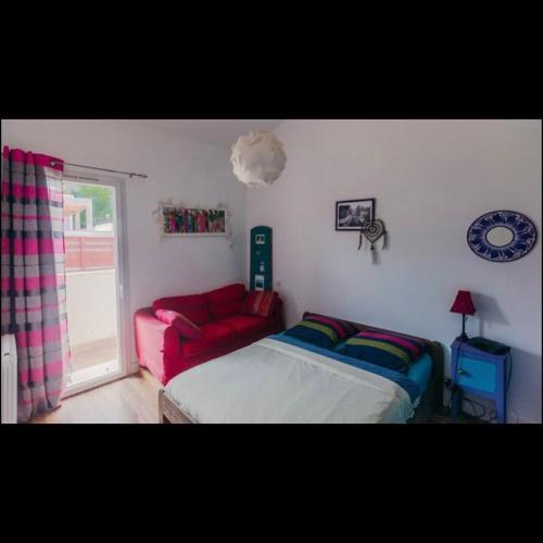 ein Schlafzimmer mit einem Bett und einem roten Sofa in der Unterkunft La petite Xabadenia in Bidart