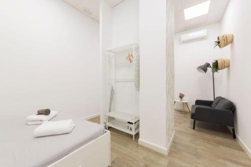 a white bedroom with a mirror and a chair at Home up Qurtuba in Córdoba