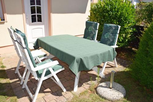 uma mesa com quatro cadeiras e uma toalha de mesa verde em Villa Vitalis Ferienhaus Vitale em Ostseebad Sellin