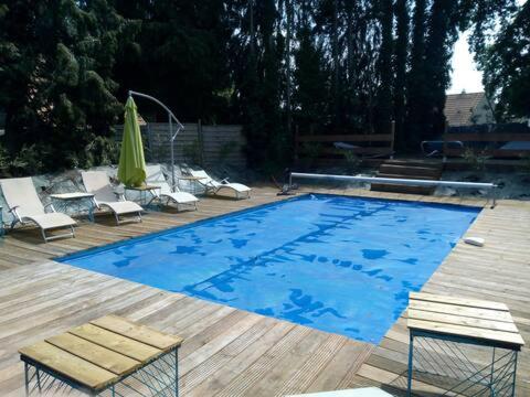 une grande piscine bleue avec des chaises et un parasol dans l'établissement annexe du manoir, à Condé-sur-Noireau