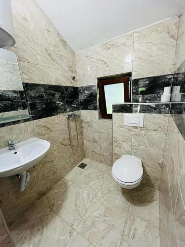 a bathroom with a white toilet and a sink at Studio Apartment in Bihać