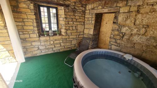 a bathroom with a large tub in a stone wall at HIŠA KAPIŠ with HOT TUBE in Koper