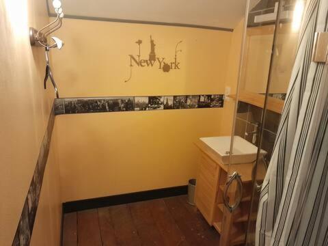 La salle de bains est pourvue d'un mur jaune, d'un lavabo et d'un miroir. dans l'établissement annexe du manoir, à Condé-sur-Noireau