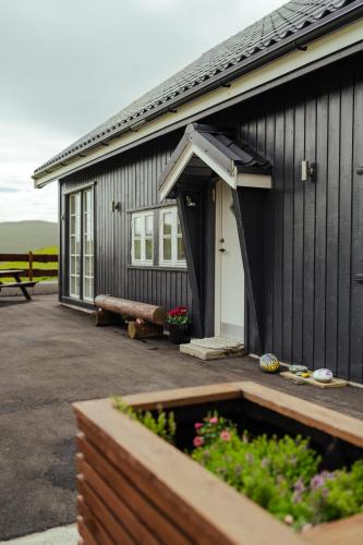 a black building with a garden in front of it at Á Snætu - Serene Village Stay Surrounded by Nature in Sandavágur