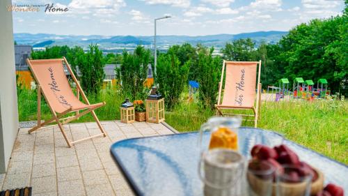 two lawn chairs and a table with fruit on it at Wonder Home - Domki Hillside tuż przy stoku narciarskim - na terenie kompleksu plac zabaw i zewnętrzna siłownia, sklep, parking in Karpacz