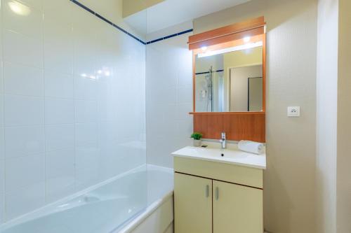 La salle de bains est pourvue d'un lavabo, d'une baignoire et d'un miroir. dans l'établissement Appart'City Confort Nantes Cité des Congrès, à Nantes