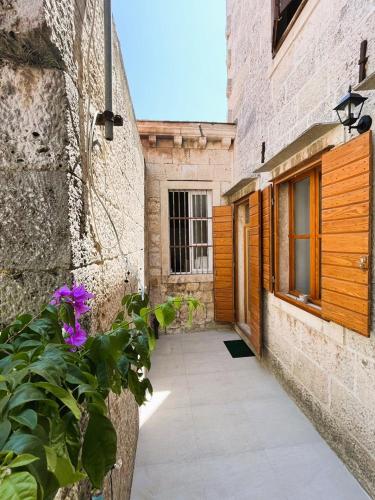 a walkway between two buildings with purple flowers at Zamaria Apartments in Vis