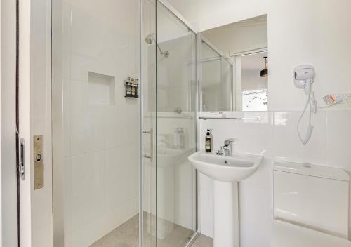 a white bathroom with a sink and a shower at Guthega Inn in Perisher Valley