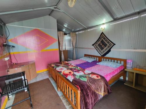 um pequeno quarto com uma cama num quarto em Himvadi Resorts Kausani em Kausani