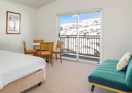 um quarto com uma cama, uma mesa e uma varanda em Guthega Inn em Perisher Valley