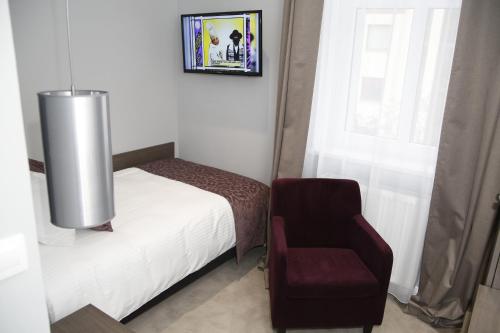 a bedroom with a bed and a chair and a window at Hotel Chopin Bydgoszcz in Bydgoszcz