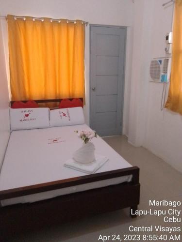 a bedroom with a bed with a vase of flowers on it at WJV INN MARIBAG0 in Maribago