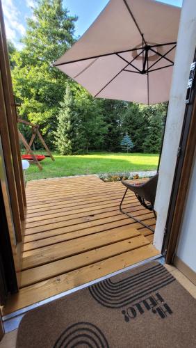 a wooden porch with an umbrella and a chair at Apartament na Kasztanowej in Piotrowice