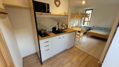 a kitchen with white cabinets and a living room at Apartament na Kasztanowej in Piotrowice