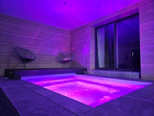 的住宿－Villa & Spa Luxuria，紫色照明的客房内的热水浴池