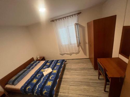 a bedroom with a bed and a desk and a window at Villa Ornella in Nečujam