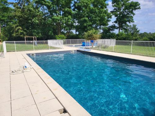 a swimming pool with blue water and a fence at La petite Maison in Ronsenac