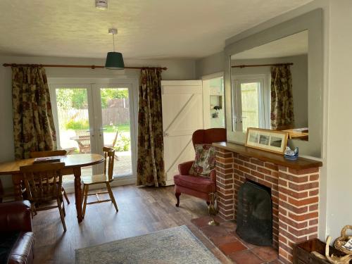 a living room with a brick fireplace and a table at Betty's Cottage - Traditional Norfolk Farm Cottage in Swafield