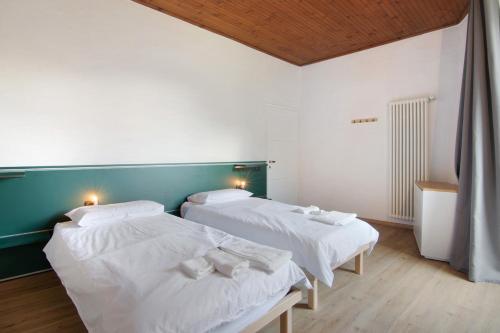 two beds in a room with white sheets at Workation Castle in Carlazzo