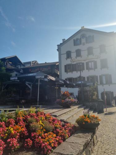 une rue avec des fleurs et des parasols en face d'un bâtiment dans l'établissement Auberge de la Bourgeoisie, à Troistorrents