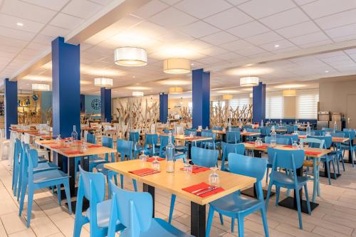 une salle à manger avec des tables et des chaises bleues dans l'établissement Azureva Pornichet Baie de La Baule, à Pornichet