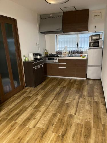 cocina con suelo de madera y cocina con nevera en ABC accommodation, en Osaka
