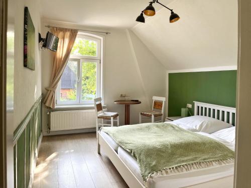 um quarto com uma cama verde e branca e uma janela em Gasthof Heidelust Pension em Undeloh