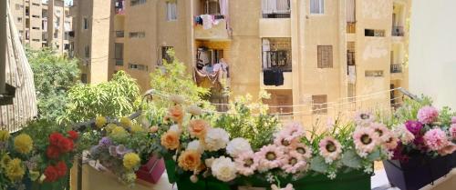 2 bedroom, 4 beds, apartment in El sheikh Zayed Cairo Egypt في Sheikh Zayed: حفنة من الزهور على شرفة المبنى