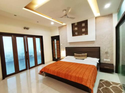a bedroom with a large bed and large windows at OM SHAKTI in Belgaum
