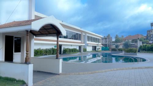 a building with a swimming pool in front of a building at Mayur Belgaum Presidency Hotel & Spa in Belgaum