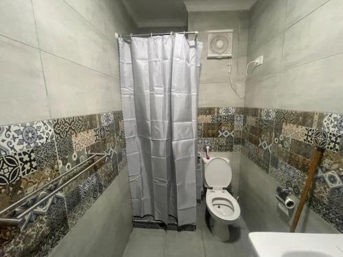 a bathroom with a toilet and a shower curtain at Porto Golf Marina Alamein in El Alamein