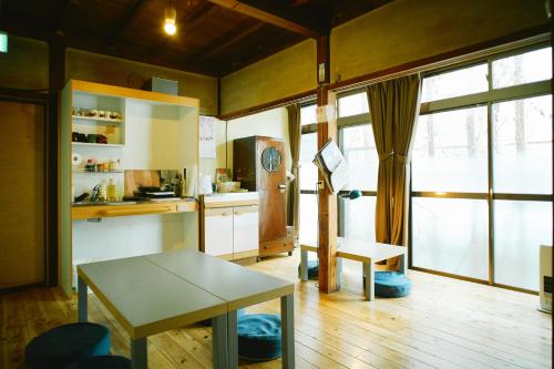 a living room with a table and a kitchen at Hostel&Bar CAMOSIBA in Yokote