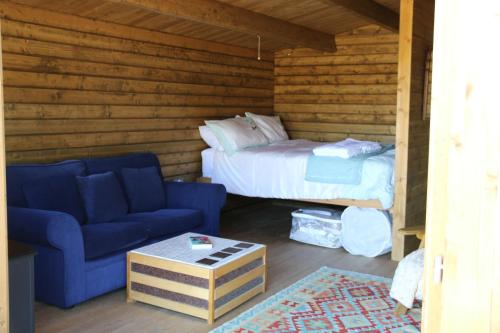 a room with a bed and a blue couch and a bed at Knapp Farm Glamping Lodge 2 in Corscombe