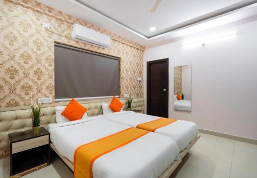 1 dormitorio con 1 cama blanca grande con almohadas de color naranja en Iris at Nest, en Hyderabad