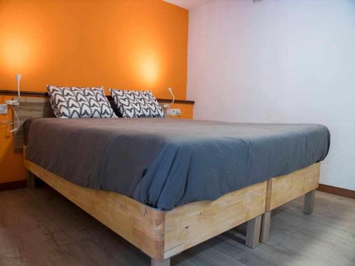 - un grand lit en bois dans une chambre dotée d'un mur orange dans l'établissement Un lugar en el mundo, à Tegueste